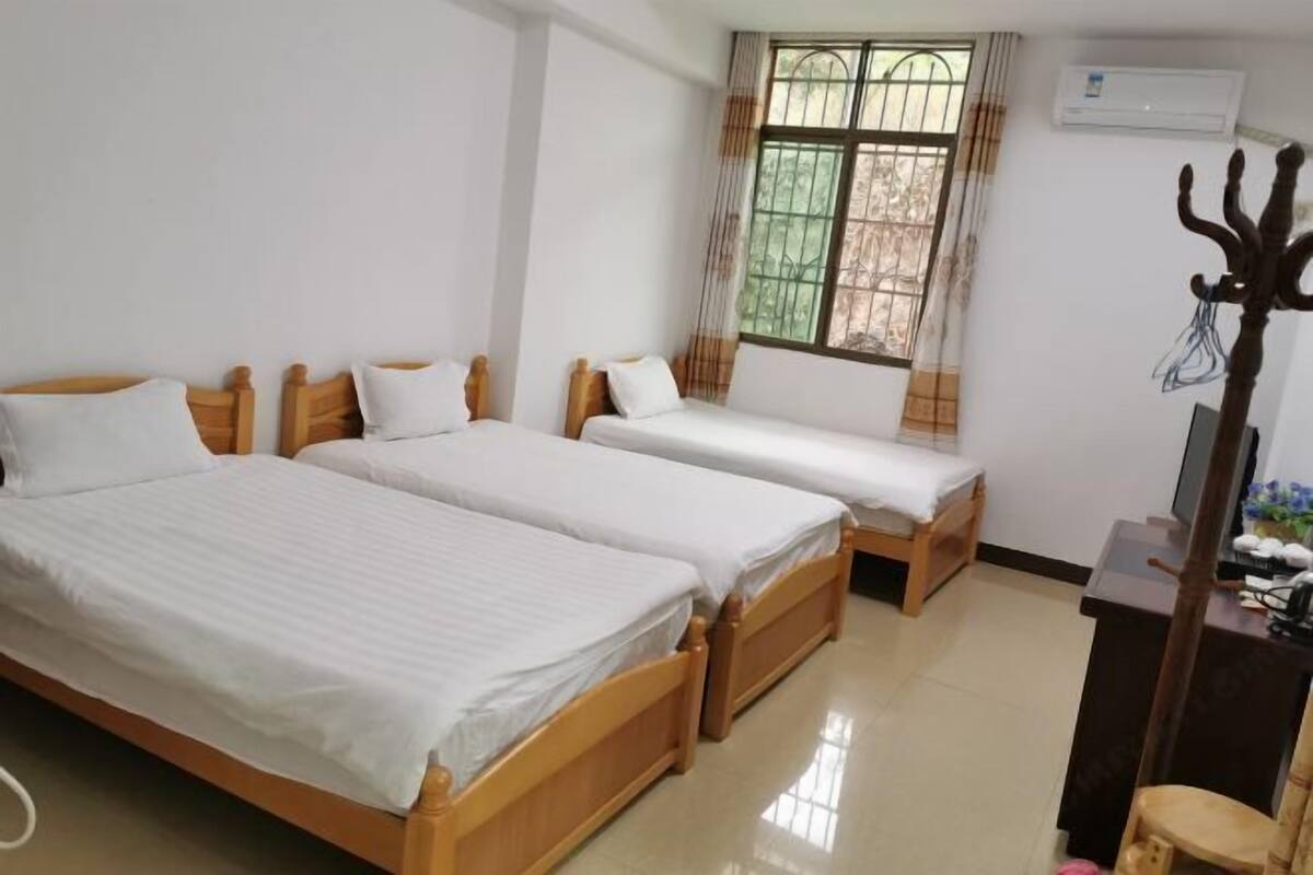A room with three wooden beds, a desk, and a chair.