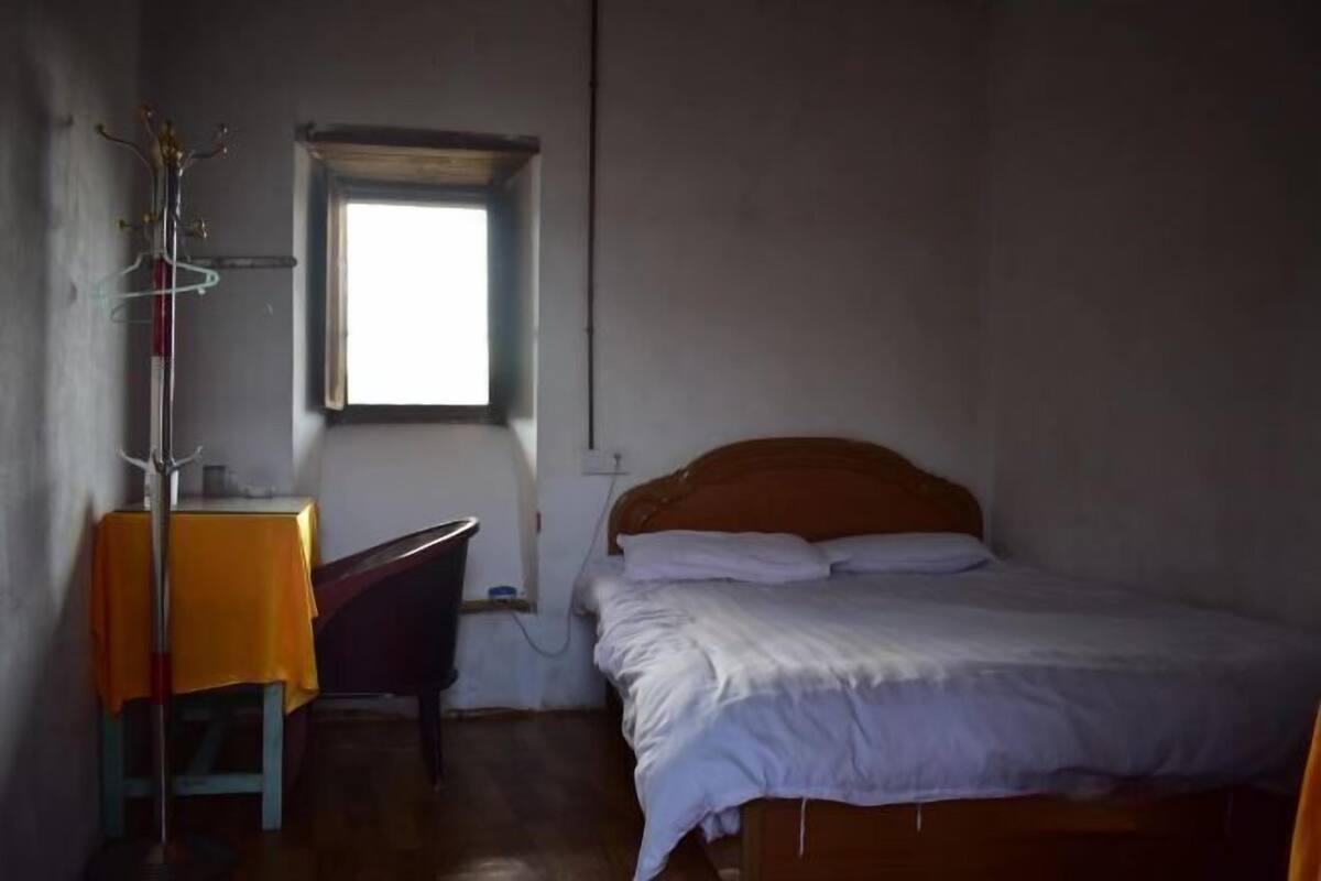 A bedroom with a bed, a window, a table, and a chair.