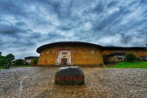 Un edificio grande y circular, con una entrada central y un monumento de piedra al frente.