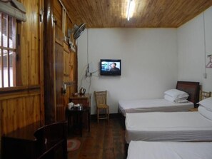 Cozy retreat with two single beds, a wooden table, and a television.
