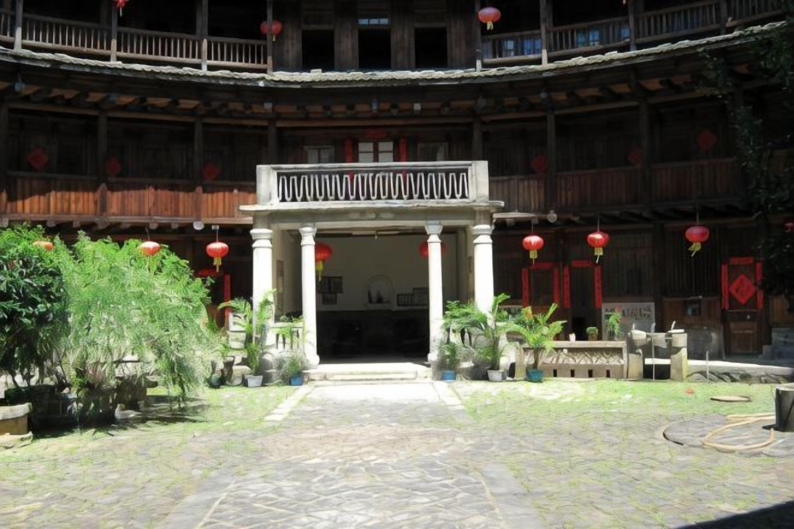 Un patio central con espacio abierto, rodeado de edificios con balcones y faroles rojos.