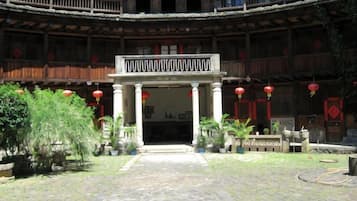 Un patio central con espacio abierto, rodeado de edificios con balcones y faroles rojos.