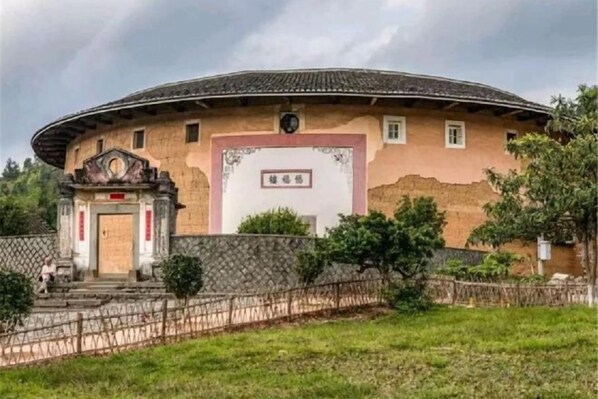A circular building with a traditional design, a small entrance with a gate, and a sign above the door.