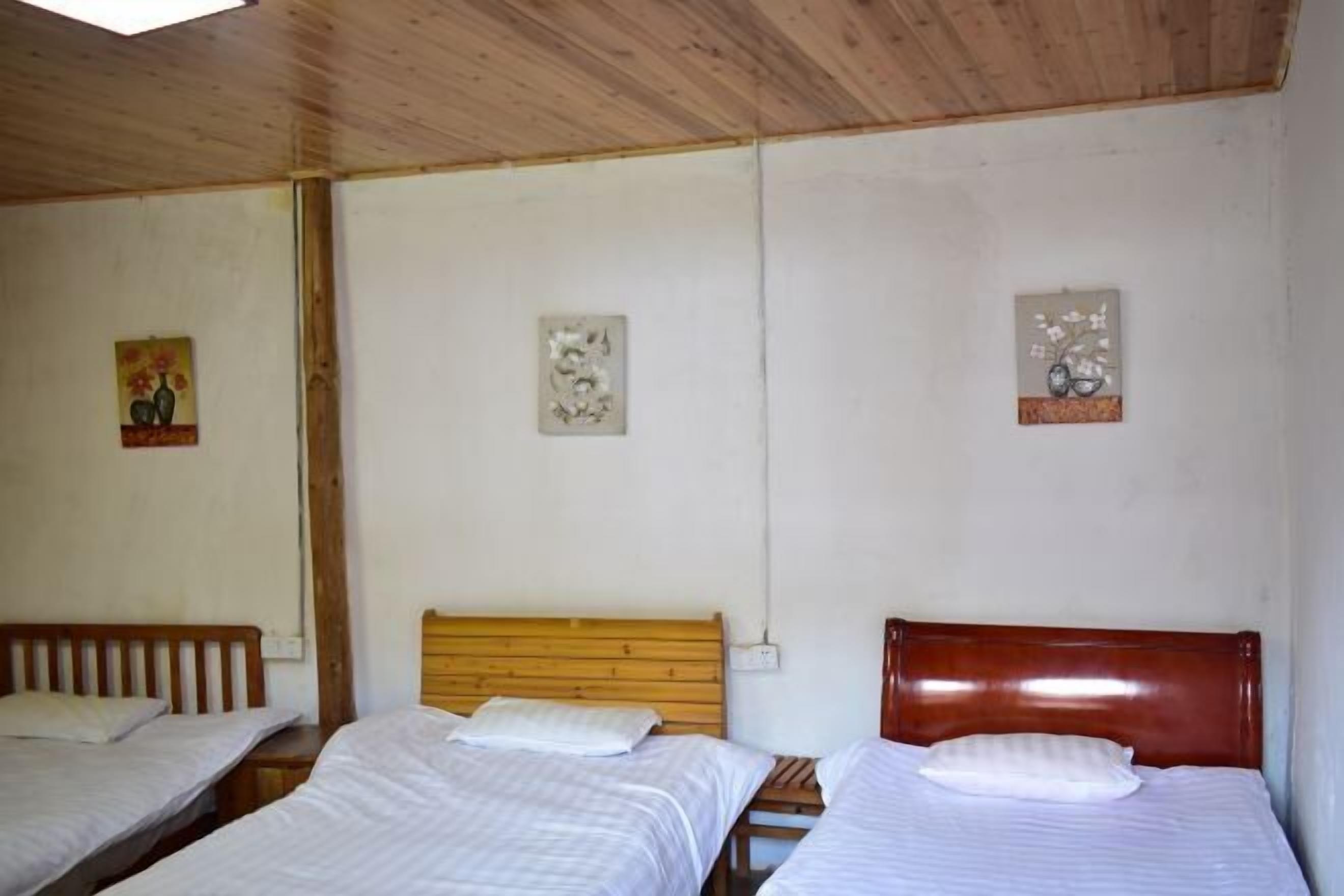 Una habitación con tres camas de madera, ropa de cama blanca y tres obras de arte colgadas en la pared.