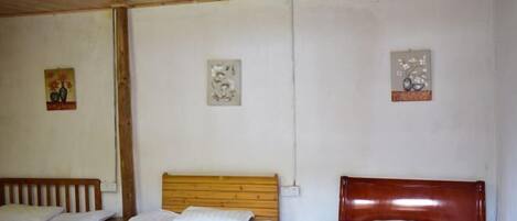 A room with three wooden beds, white bedding, and three wall-mounted artworks.