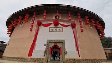 Un edificio tradicional con estructura circular, una entrada central y decoraciones rojas.