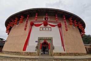 A traditional building with a circular structure, a central entrance, and red decorations. - Yongding Qiaofu Building Doctor Home Inn (Longyan)