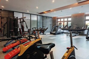 A gym with various exercise equipment, including treadmills and stationary bikes, and a large window providing natural light. - Freely Hover Golden Shuitai Hot Spring Town (Xinxing)