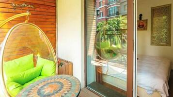 A room with a hanging chair, a bed, and a view of a building through a glass door.