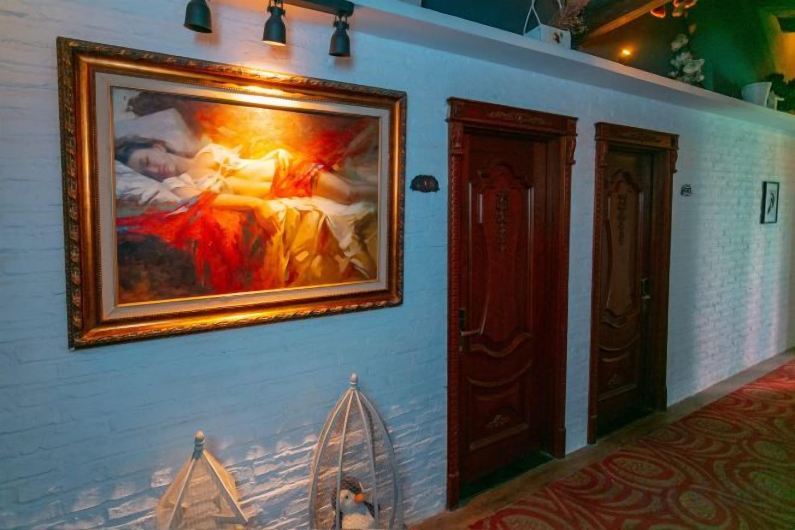 A hallway with a framed painting, two wooden doors, and a patterned carpet.