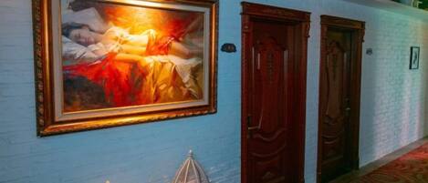A hallway with a framed painting, two wooden doors, and a patterned carpet.