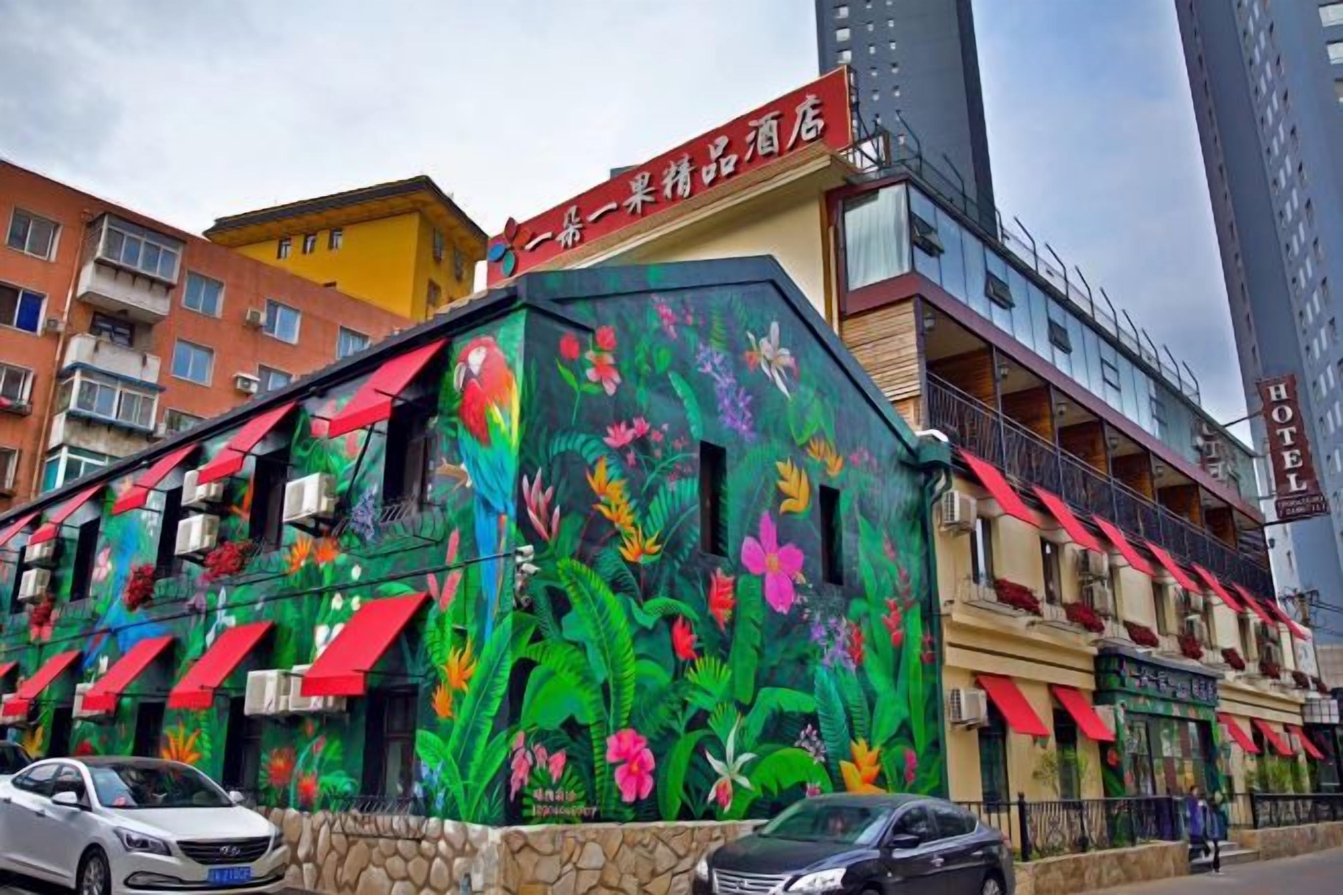 A hotel with colorful exterior murals, multiple balconies, and a visible restaurant.