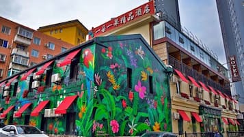 A hotel with colorful exterior murals, multiple balconies, and a visible restaurant.