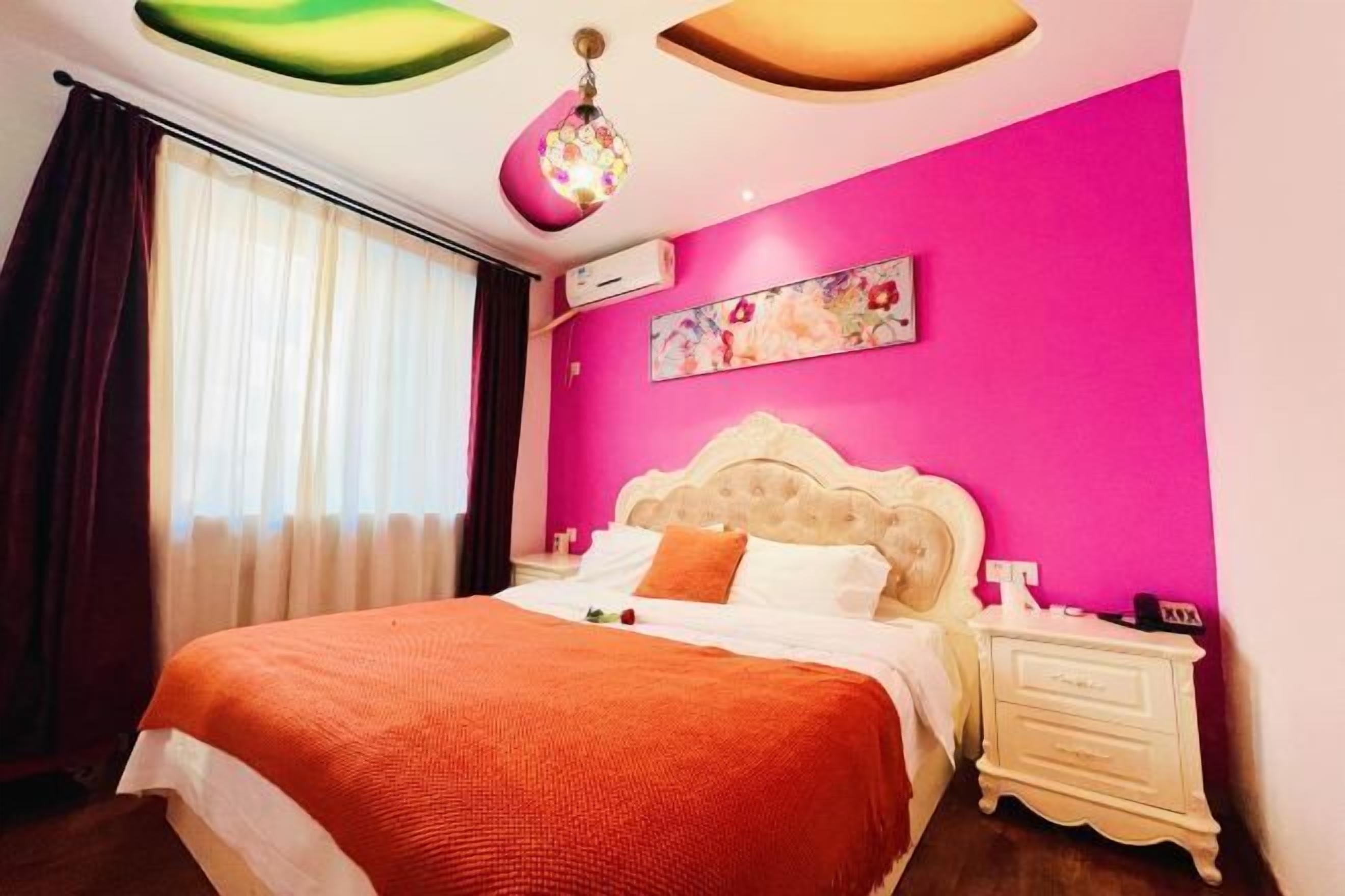 A bedroom with a bed, a nightstand, a wall-mounted air conditioner, and a window with curtains.
