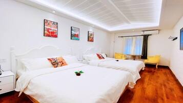 A hotel room with two beds, white bedding, a wooden floor, and artwork on the walls.