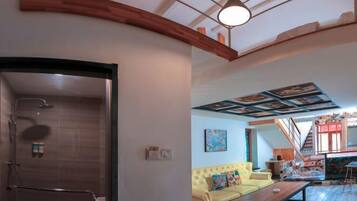 A modern interior with a shower, a yellow sofa, and a wooden ceiling.