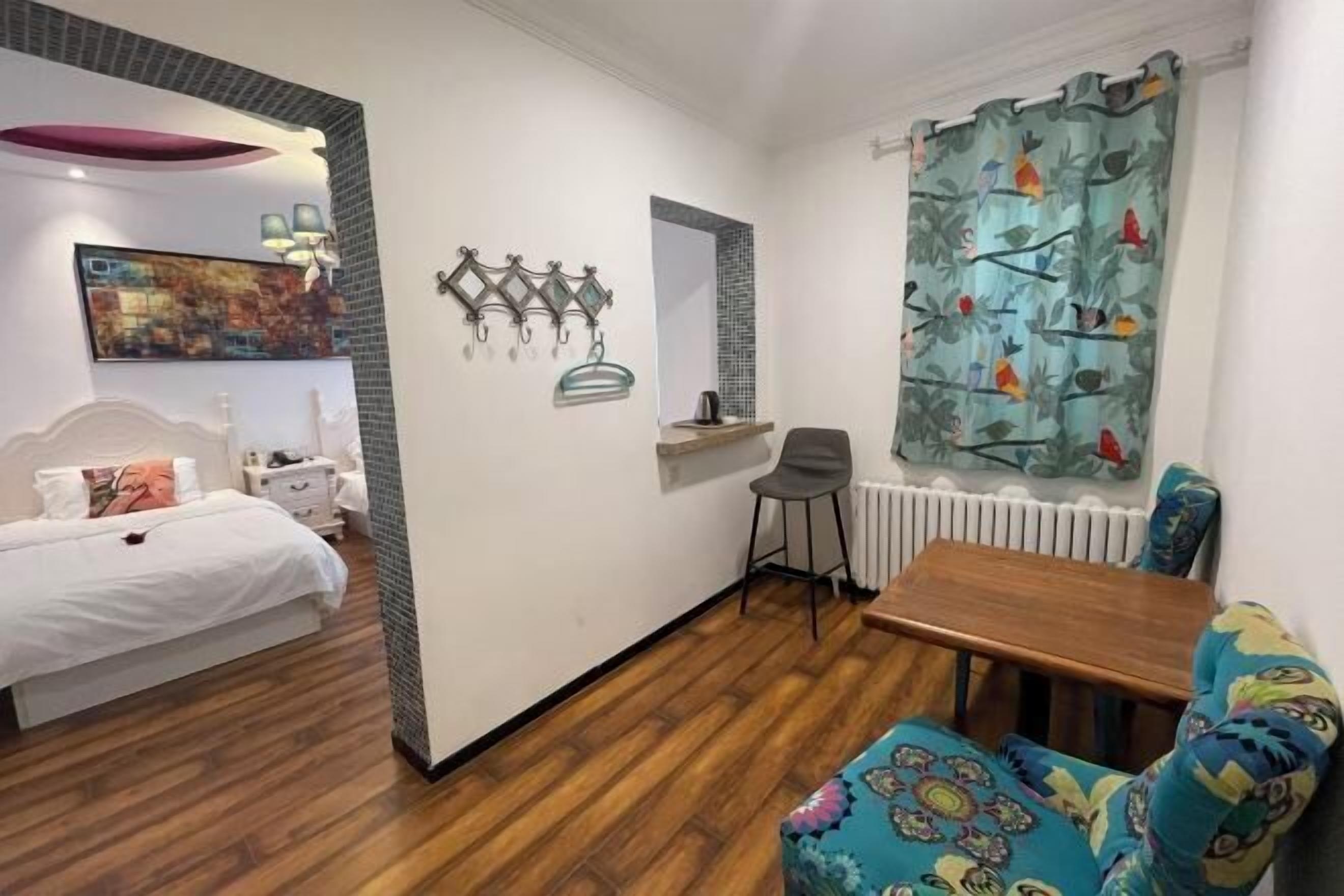 A bedroom with a bed, bedside table, chair, and a small table with a chair.