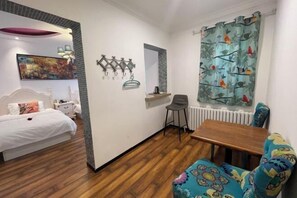 A bedroom with a bed, bedside table, chair, and a small table with a chair.