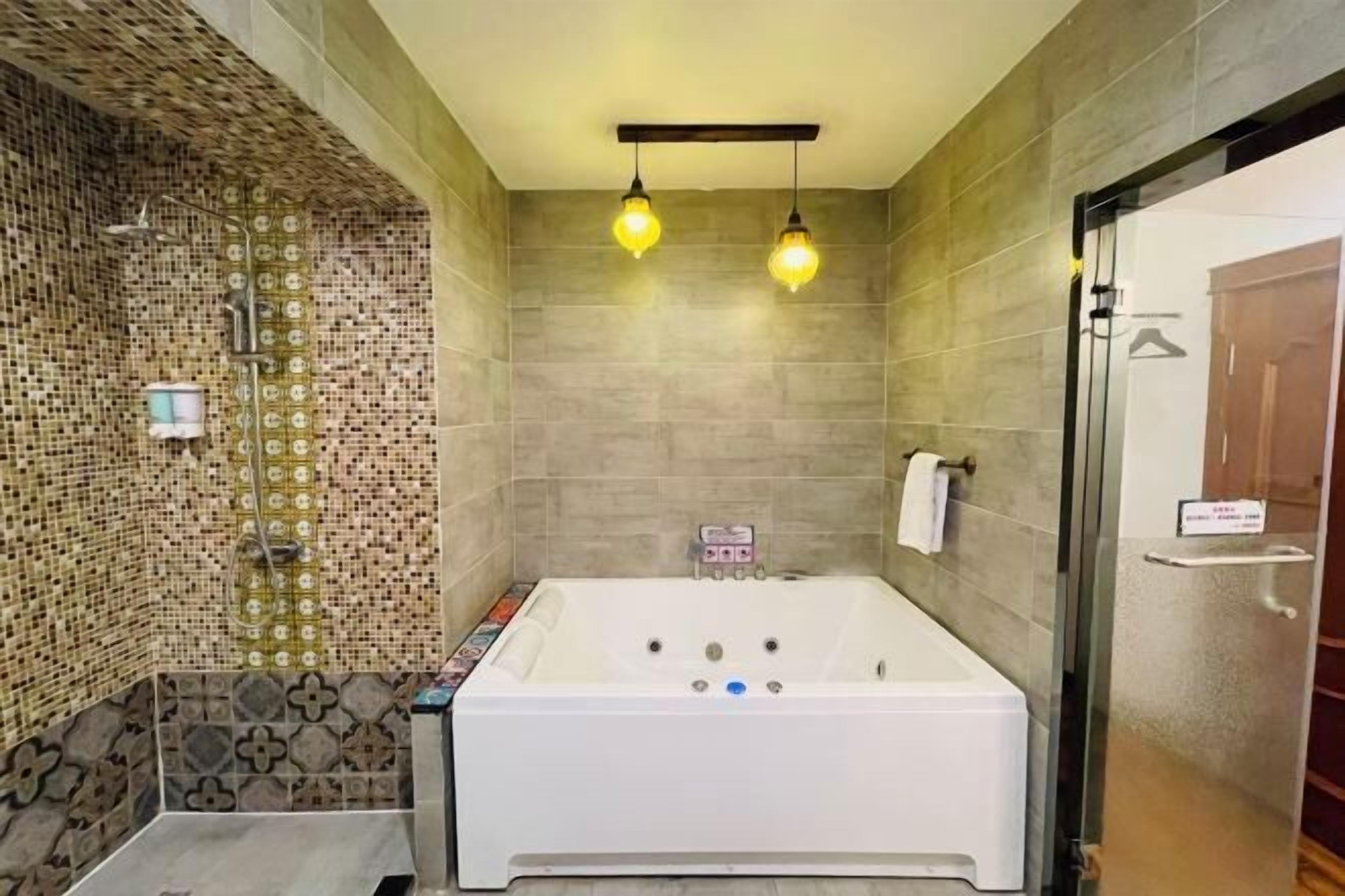 A modern bathroom with a large bathtub, a shower area with mosaic tiles, and two pendant lights.
