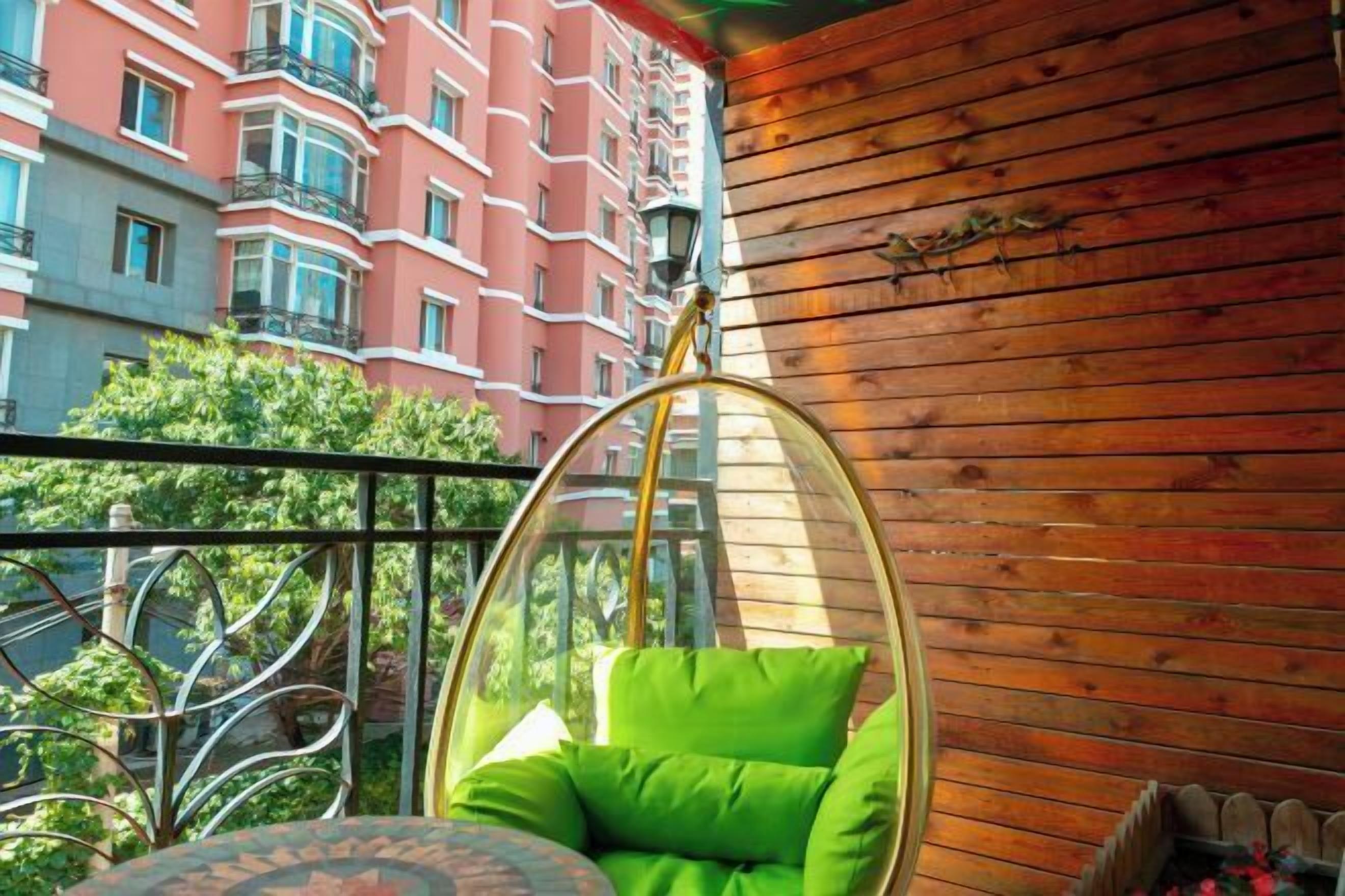 A hanging chair with a cushion, a wooden wall, and a balcony with a view of a red building.
