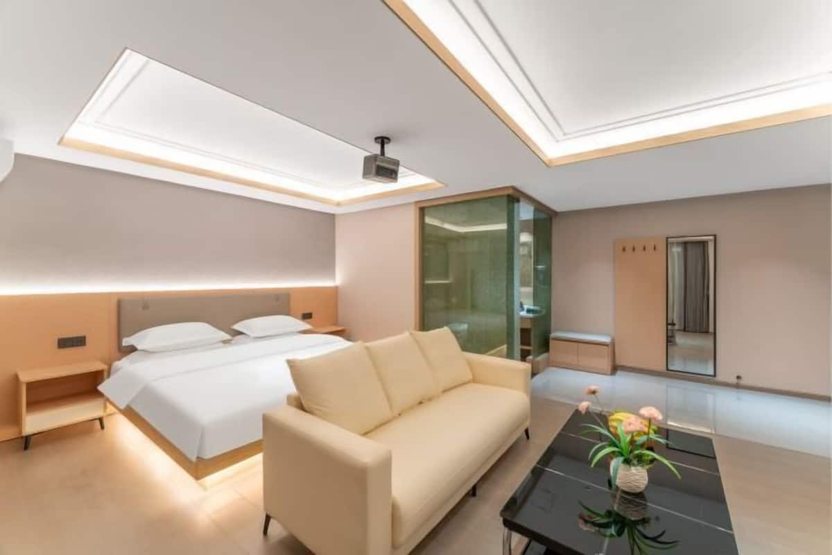 Une chambre d’hôtel moderne équipée d’un lit, d’un canapé, d’un bureau et d’une cloison en verre.