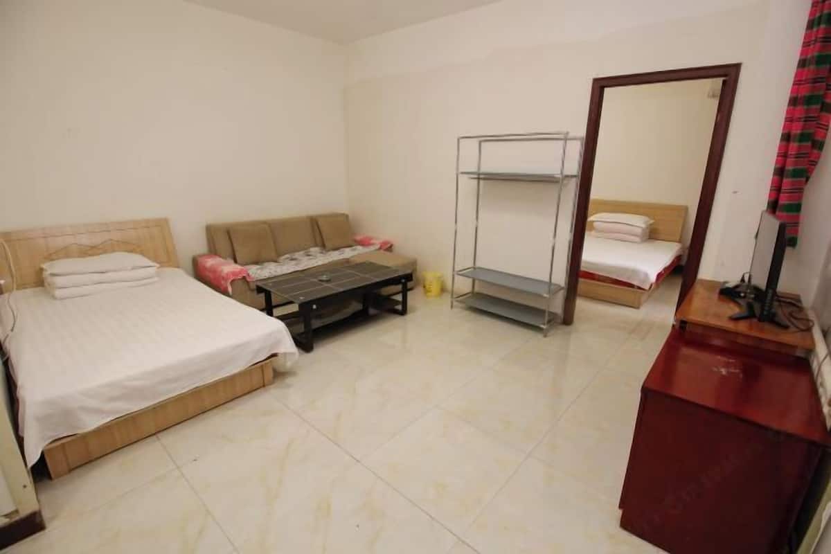A room with two beds, a small table, a mirror, and a red cabinet.