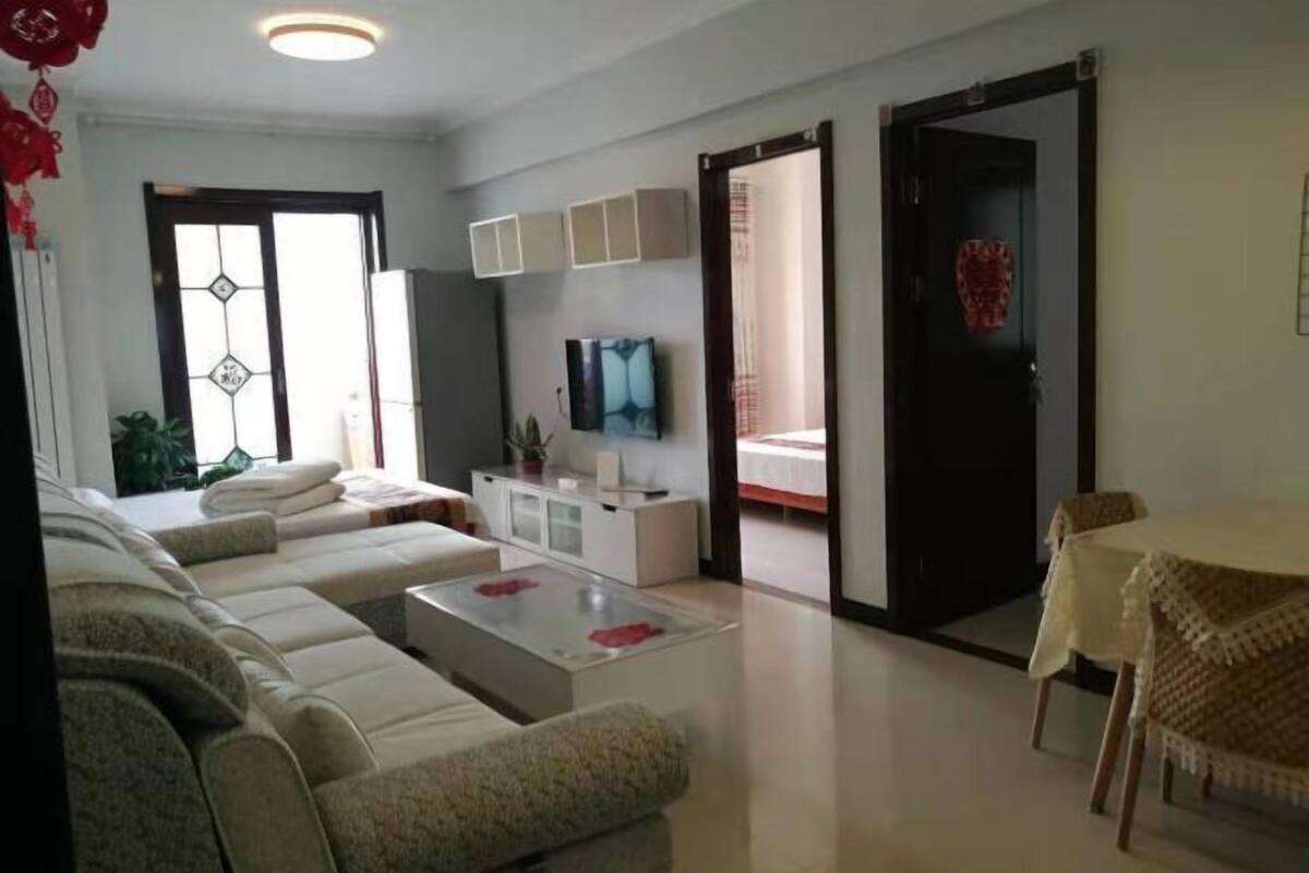 A living room with a sofa set, a coffee table, a TV, and a dining area with a table and chairs.