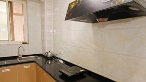 Een keuken met een zwart aanrecht, een waterkoker, een weegschaal en een raam met jaloezieën.