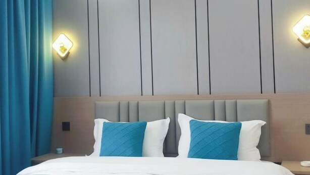 A hotel room with a bed, two wall-mounted light fixtures, and a headboard. - Beihai Wangzu Hotel (Beihai)