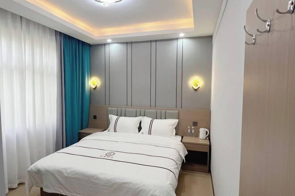 Een hotelkamer met een bed, nachtkastje en wandlampen.