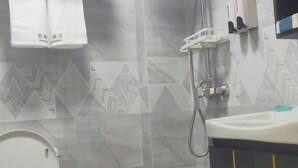 A bathroom with a shower, a sink, and a toilet. - Beihai Wangzu Hotel (Beihai)