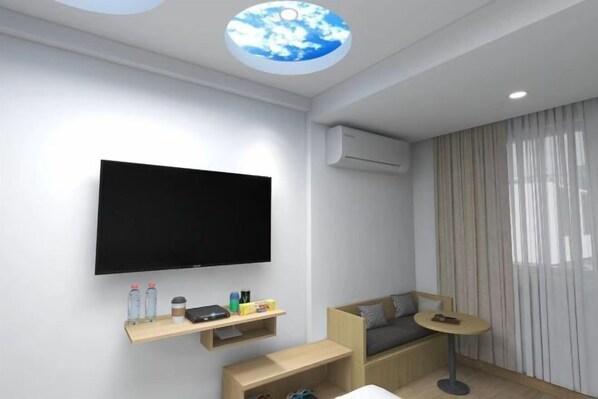 A modern living room with a flat-screen TV, wooden shelves, a sofa, a small round table, and a ceiling with a circular skylight.