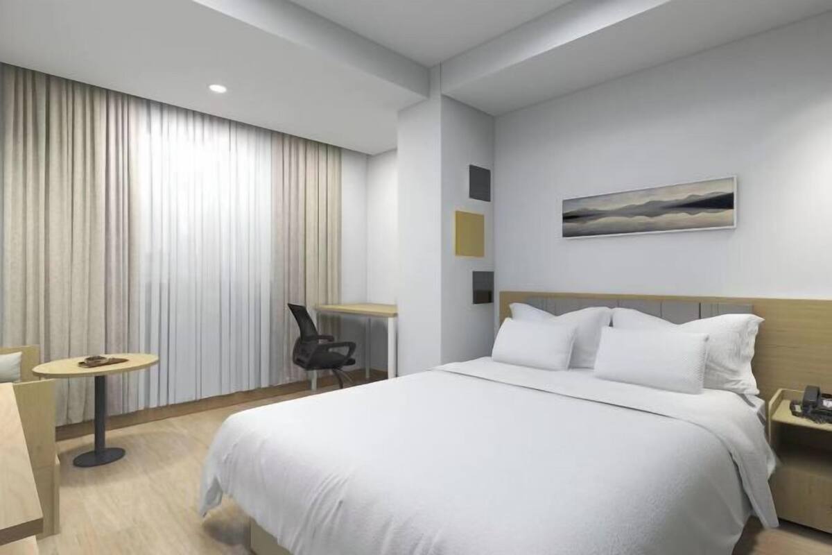 Una habitación de hotel con una cama, un escritorio, una silla y un cuadro en la pared.