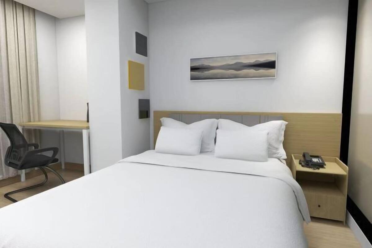 Una habitación de hotel moderna con una cama grande, un escritorio y una silla.