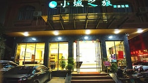 A building with a sign that reads '小城之旅' and a car parked in front. - Xiaocheng Zhilv Hotel (Cenxi)
