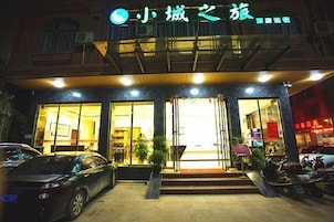 Un edificio con un cartel que dice '小城之旅' y un coche estacionado al frente.