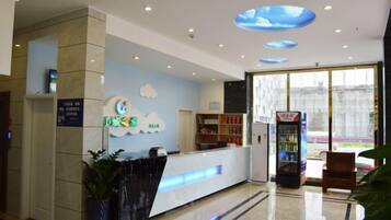 A hotel reception area with a reception desk, a vending machine, and a large window.