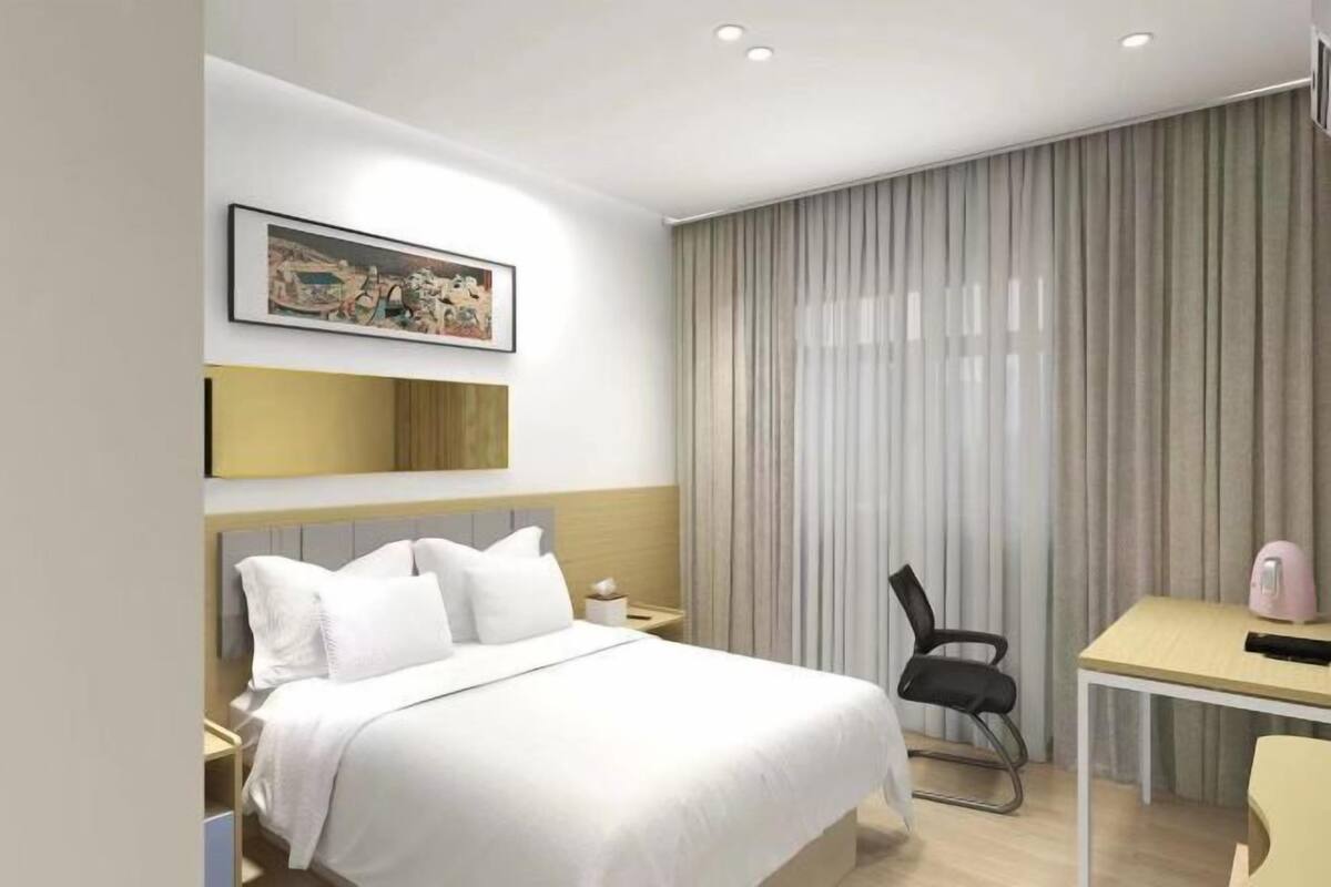 Una habitación de hotel moderna con una cama grande, un escritorio, una silla y un cuadro en la pared.