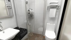 A bathroom with a white sink, a toilet, a glass shower enclosure, and a towel rack. - Xiaocheng Zhilv Hotel (Cenxi)