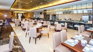 Ein geräumiges Restaurant mit mehreren Tischen und Stühlen, einem Marmorboden und einer modern gestalteten Küchenzeile.