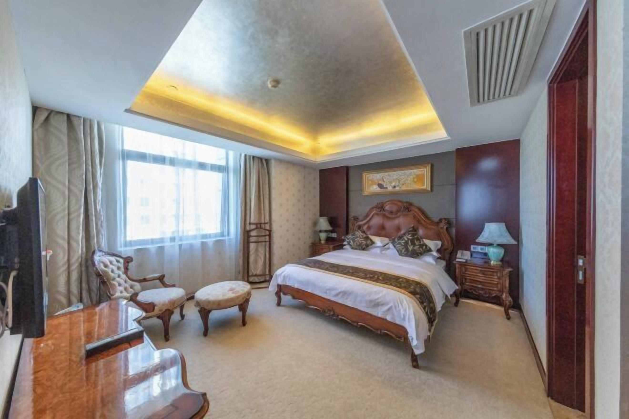 Une chambre d’hôtel avec un grand lit, un bureau, une chaise et un téléviseur.