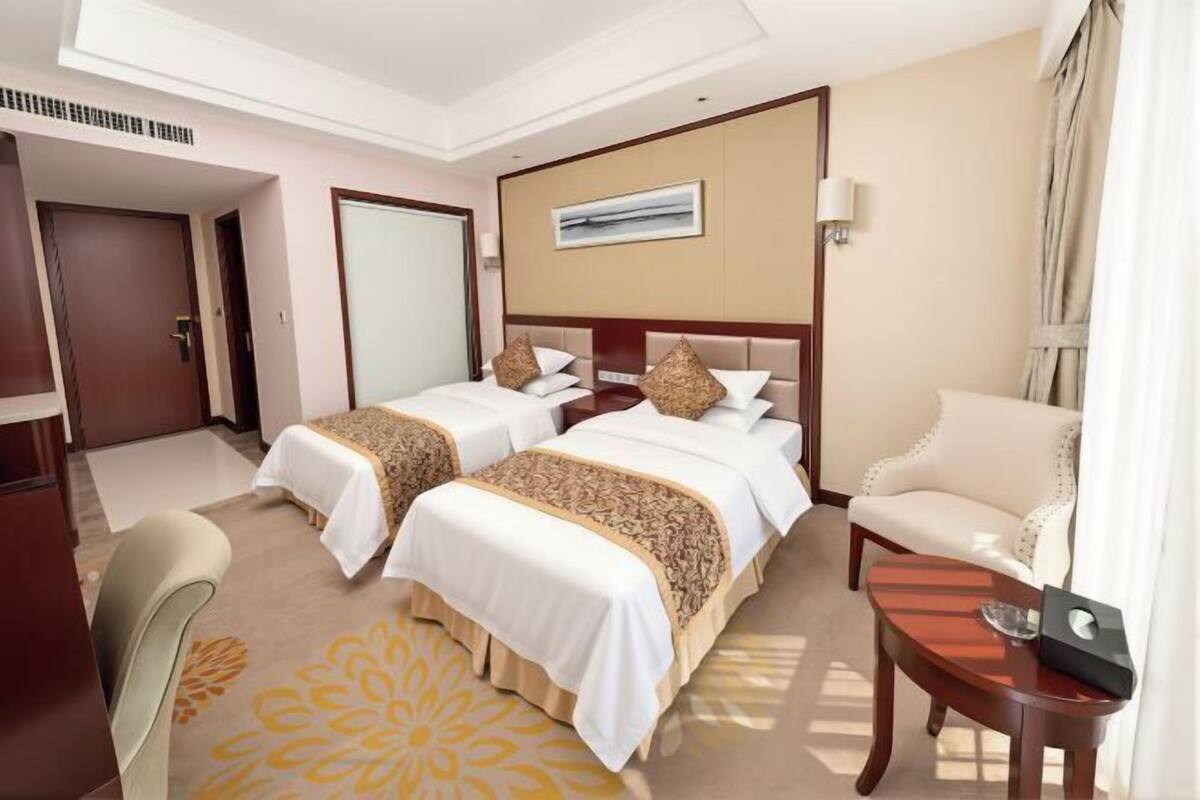 Habitación de hotel con dos camas, un sofá, un escritorio y una silla.