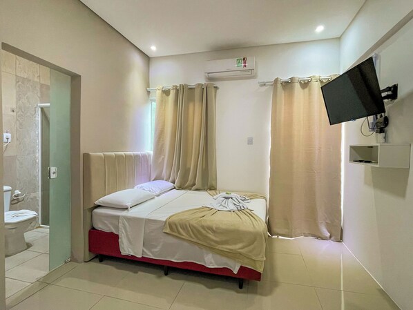 A bedroom with a bed, a television mounted on the wall, and an air conditioning unit. - Pousada Mel e Mar (Penha)