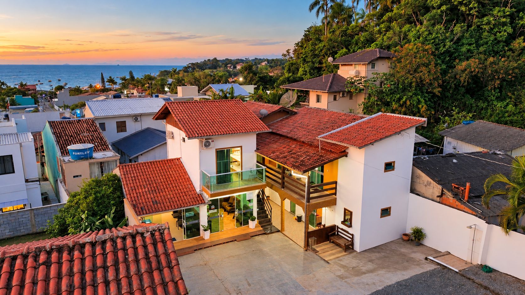 Um edifício residencial com telhado de telhas vermelhas, varanda e vista para o mar.