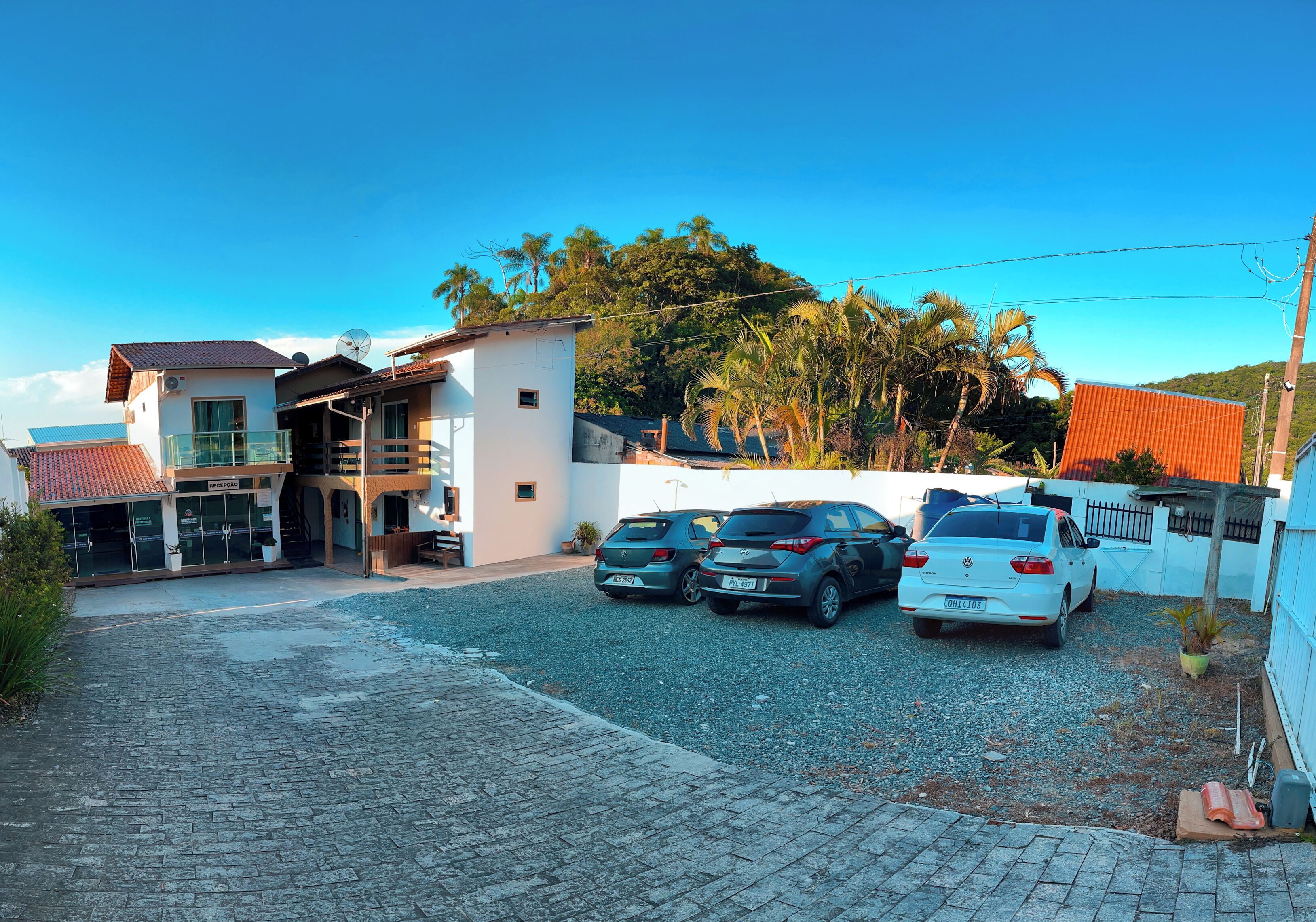 A residential area with a paved driveway, parked cars, and a building with a balcony.