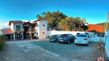 A residential area with a paved driveway, parked cars, and a building with a balcony.