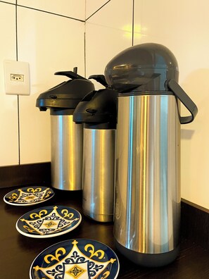 Stainless steel thermos flasks and decorative plates on a wooden table. - Pousada Mel e Mar (Penha)