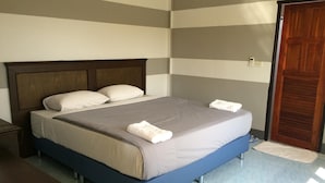 A hotel room with a bed, a wooden headboard, a nightstand, and a door.
