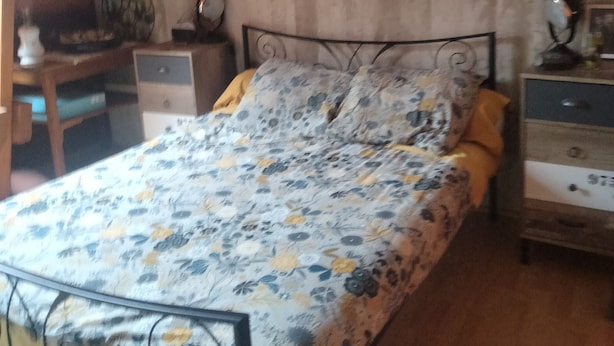 A bedroom with a bed, two bedside tables, a nightstand, a painting, and a ceiling fan. - La Chapelle (Teloché)
