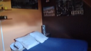 A bedroom with a bed, a nightstand, a lamp, and a wall with pictures. - La Chapelle (Teloché)